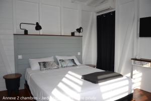 a bedroom with a white bed and a window at Villa Coco Cannelle in Deshaies