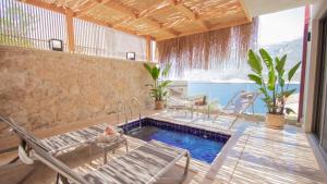 a swimming pool in a room with chairs and a table at Adasya Hotel in Kaş