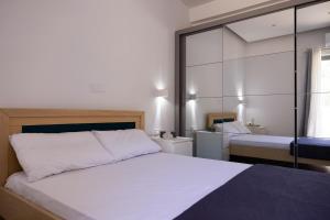 a bedroom with a large white bed and a mirror at Lontos Luxury Seaside House in Flampouria