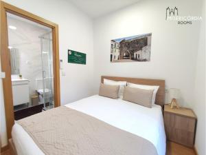 a bedroom with a white bed and a bathroom at Misericórdia Rooms in Guarda
