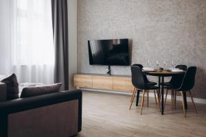 a living room with a table with chairs and a television at Apartament Centrum Żywiec - GROJEC in Żywiec