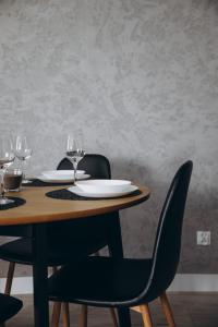a wooden table with chairs and plates and wine glasses at Apartament Centrum Żywiec - GROJEC in Żywiec
