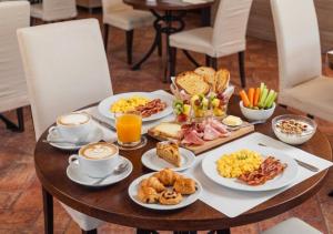 a table topped with plates of breakfast foods and cups of coffee at La Vecchia Fonte Boutique Hotel in Palau