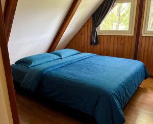 a bed with blue sheets in a room with a window at Utpuster in Lauwersoog