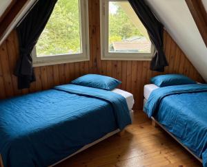 two beds in a room with two windows at Utpuster in Lauwersoog
