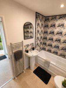 a bathroom with a sink and a tub and a toilet at Brae Lodge Dollar in Dollar