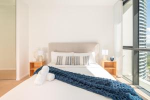 a bedroom with a large white bed with a blue blanket at Modern Broadbeach 2BR Apartment - Pet Friendly in Gold Coast