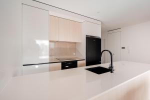 a kitchen with a white counter and a black refrigerator at Modern Broadbeach 2BR Apartment - Pet Friendly in Gold Coast