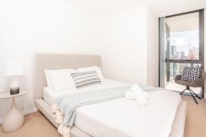 a white bedroom with a bed and a window at Modern Broadbeach 2BR Apartment - Pet Friendly in Gold Coast +10 photos