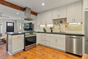 a kitchen with white cabinets and stainless steel appliances at Templeton Creekside Cottage Walk to Downtown in Templeton