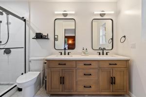 a bathroom with a sink and a toilet and two mirrors at Templeton Creekside Cottage Walk to Downtown in Templeton