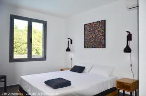 a white bedroom with a bed and a window at Villa Coco Cannelle in Deshaies