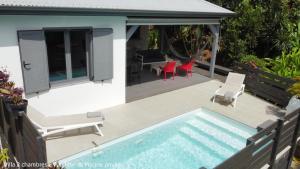 a swimming pool with chairs and a table and a house at Villa Coco Cannelle in Deshaies
