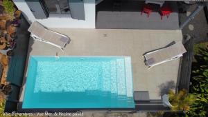 an overhead view of a swimming pool with two chairs at Villa Coco Cannelle in Deshaies