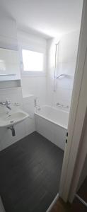 a white bathroom with a tub and a sink at Sensi Living Dorf in Freienbach +15 photos