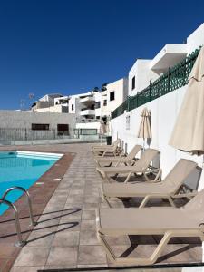 a row of chaise lounge chairs next to a swimming pool at Lovely apartment 2 rooms with big terrace in Puerto Rico in Puerto Rico de Gran Canaria