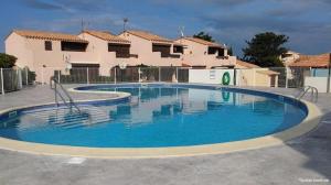 a large pool with blue water in front of a house at 423 Résidence Aphrodite naturiste in Leucate-Plage