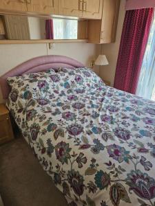 a bed with a flowered comforter on it in a bedroom at Bella in Skegness