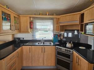 a kitchen with wooden cabinets and a sink and a stove at Bella in Skegness