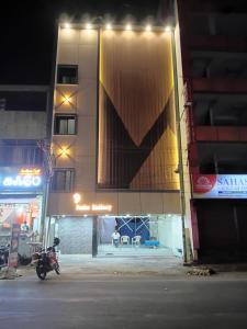 a motorcycle parked in front of a building at night at Femina Residency in Kumbakonam +14 photos