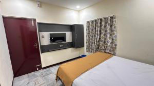 a bedroom with a bed and a tv on the wall at Femina Residency in Kumbakonam
