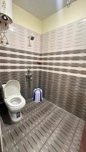 a bathroom with a toilet with a blue bag on the floor at Femina Residency in Kumbakonam