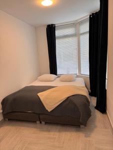 a bed in a room with a window with black curtains at Smile home, Zaanse schans and Amsterdam Appartements in Wormerveer