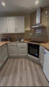 a kitchen with white cabinets and a stove top oven at Sperrin Way Apartment in Newtownstewart