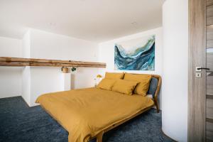 a bedroom with a bed with yellow sheets and a painting at Turistka Loft in Kutná Hora