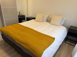 a bed with a yellow blanket on top of it at Hugleikshus in Hvolsvöllur +5 photos