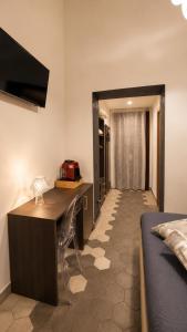 ein Schlafzimmer mit Schreibtisch und Bett sowie ein Flur in der Unterkunft Alterego B&B in Milazzo