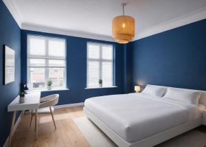 a blue bedroom with a white bed and a desk at Greenbrook Blue Suite in Aalborg