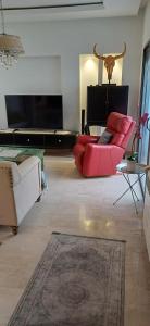 a living room with a red couch and a flat screen tv at Ville n4 in Sidi Daoud
