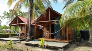 a wooden house with a hammock in front of it at Palmar Beach Cabañas - Bahía Rada in Moñitos