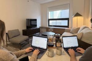 two people working on their laptops in a living room at Court Square Hotel Long Island City New York , Belvilla District 6 Formerly Sonder in Long Island City
