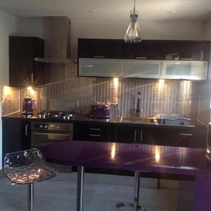 Pen Coed Cwtch Apartment في ساندرزفوت: مطبخ مع طاولة أرجوانية وقمة أرجوانية