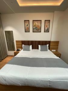 a bedroom with a large bed with three pictures on the wall at Hotel jbs inn in Jaipur