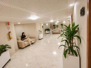 a woman sitting on a couch in a waiting room at Hotel Aikos in Yumbo
