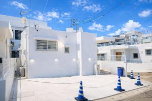 a white house with blue cones in front of it at Dual Life House Koza in Okinawa City