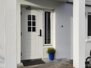a white door with a plant in a blue pot at Førde sentrum - Lindbøen Gjesterom in Førde