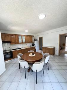 a kitchen with a wooden table and white chairs at Kovač Home in Posušje