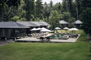 a resort with a pool and tables and chairs and umbrellas at Bobocha Tangkoko Nature Resort in Bitung