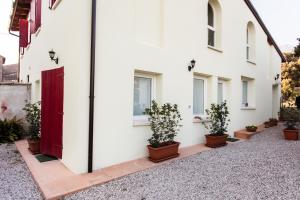 un edificio bianco con una porta rossa e piante in vaso di Appartamento Montegrappa a Crespano del Grappa