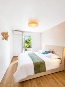 a white bedroom with a large bed and a window at Refuge des Plages-T3 neuf climatisé - Terrasse Sud - proche mer et port à Fréjus in Fréjus