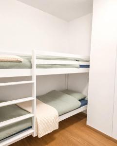a room with bunk beds in a white room at Refuge des Plages-T3 neuf climatisé - Terrasse Sud - proche mer et port à Fréjus in Fréjus