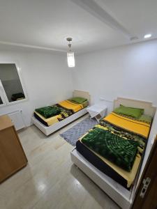 two beds in a white room with a window at Appartement Iris in Gabès