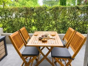 a wooden table with three chairs and wine glasses at Refuge des Plages-T3 neuf climatisé - Terrasse Sud - proche mer et port à Fréjus in Fréjus +31 photos