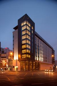 um edifício alto com muitas janelas numa rua em The Fitzwilliam Hotel Belfast em Belfast