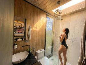 a woman in a black bathing suit standing in a bathroom at Tiny house, comfort and peace facing Chimborazo in Riobamba +23 photos