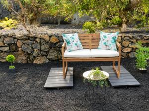 a wooden bench with two pillows on a patio at Inn Fraga in Ribeirinha